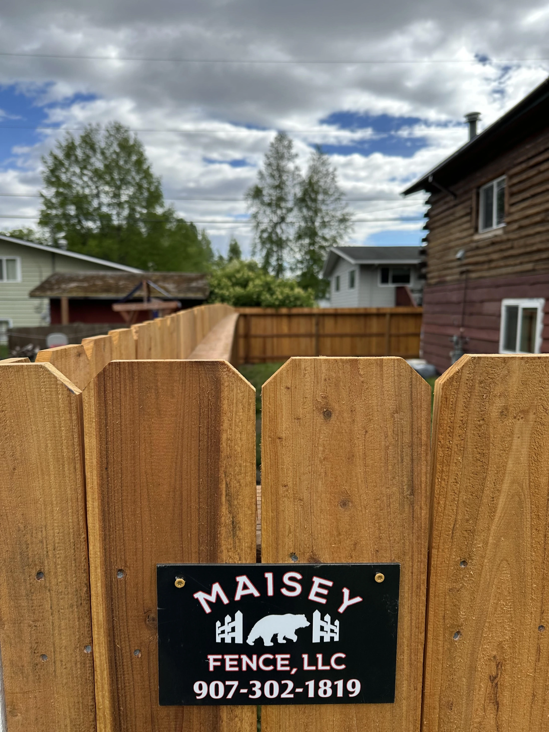 Cedar dog-eared privacy fence with Maisey Fence LLC branded sign in Anchorage