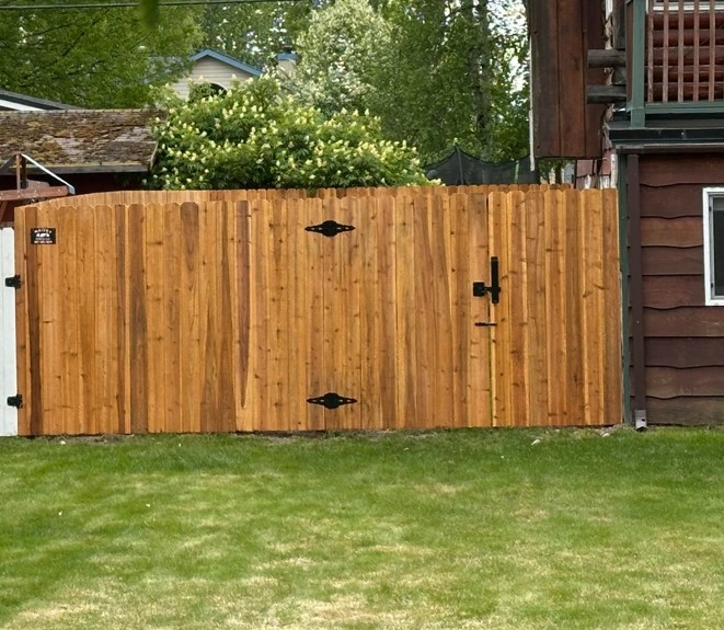 Custom prestained cedar double drive gate with heavy black hinges by Maisey Fence